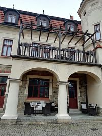 arkády a balkón nad nimi zdobený dreveným zábradlím a pergolou