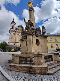 morový stĺp, za ním kostol Zvestovania Panny Márie