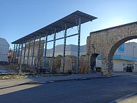 brána a poblíž asi pozostatky mestského hradu chránené kovovou konštrukciou