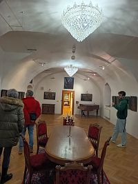 spoločenská miestnosť s obrazmi, klavírom a stolom