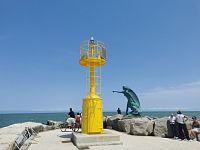 žltý maják s bronzovou sochou matky na móle Molo di Levante Capitan Giulietti
