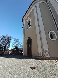 vchodov do kostola pod varhanmi, v pozadí pri zaparkovanom aute ssúsošie Svätá rodina