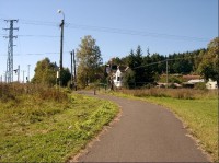 Ze severovýchodu: Pohled z neznačené cesty na rozcestník (sloup el. vedení vlevo od cesty).