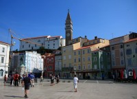 Piran- Tartiniho náměstí  s romantickým jeřábem. V popředí Červený Benátský dům a nad ním Kostel sv. Jiří