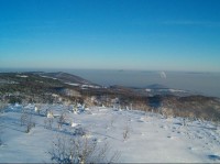 Panorama 3: Pohled na Krušné hory s Vlčí horou (vlevo se stožárem), Stropníkem a Špičákem (zhruba uprostřed), České středohoří nad inverzní hladinou s Milešovkou