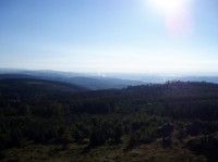 výhled z Meluzíny: příkré svahy Krušných hor nad Chomutovskou pánví, kde kouří Prunéřov, vpravo na obzoru Nechranice