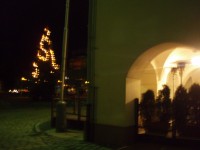 Podloubí budovy muzea s pizzerií a rozsvícený vánoční strom